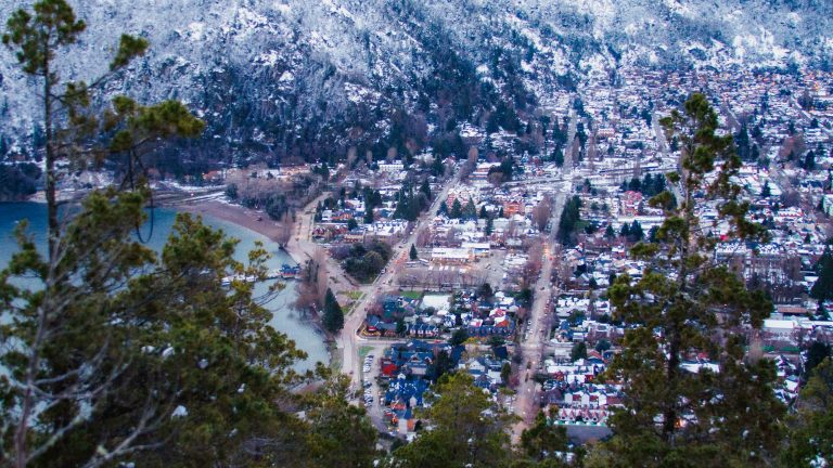Vista aérea de San Martín de los Andes en invierno con nieve y árboles.
