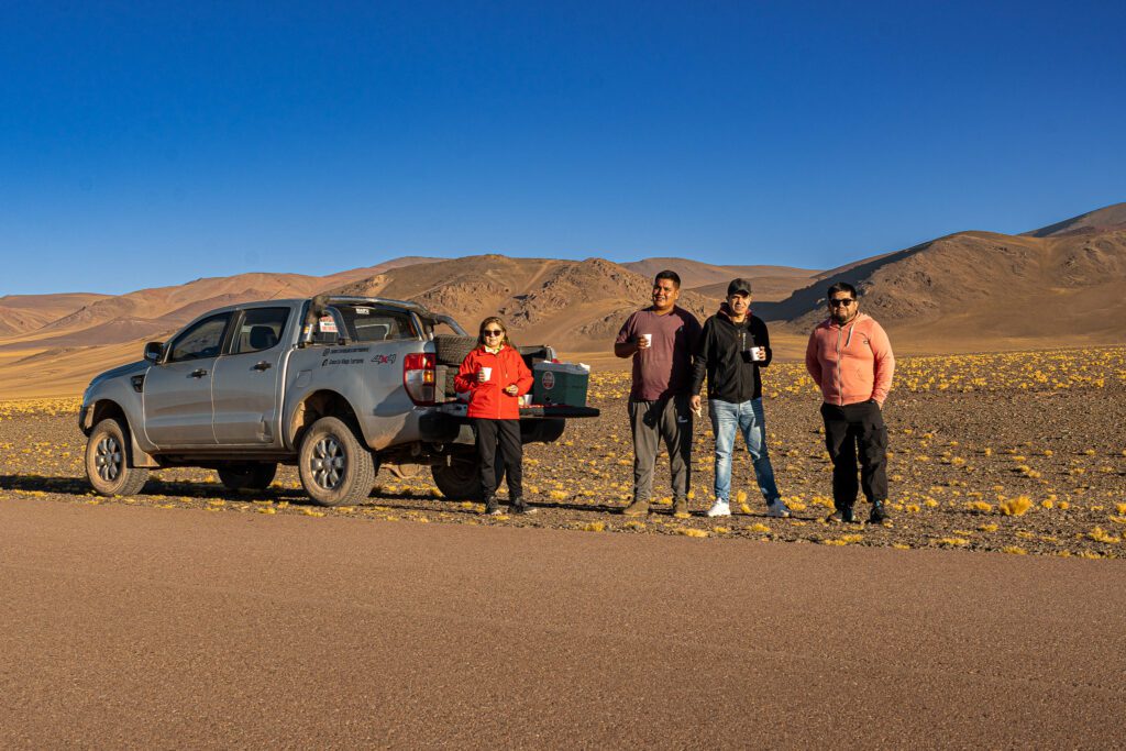 Grupo de viajeros y guías junto a la 4x4 de Cuesta Vieja Turismo, con mate en mano, en un alto del camino hacia el Cráter Corona del Inca, La Rioja