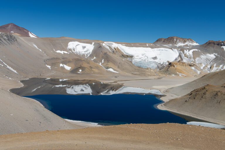 Laguna de agua azul profunda en un circo de montañas nevadas y glaciares, el Cráter Corona del Inca, a más de 5.500 msnm en La Rioja