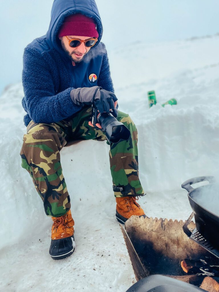 Gustavo Arias con una cámara Sony Aplha 4 grabando el momento en que se hace un risotto en una olla de hierro en medio de la nieve