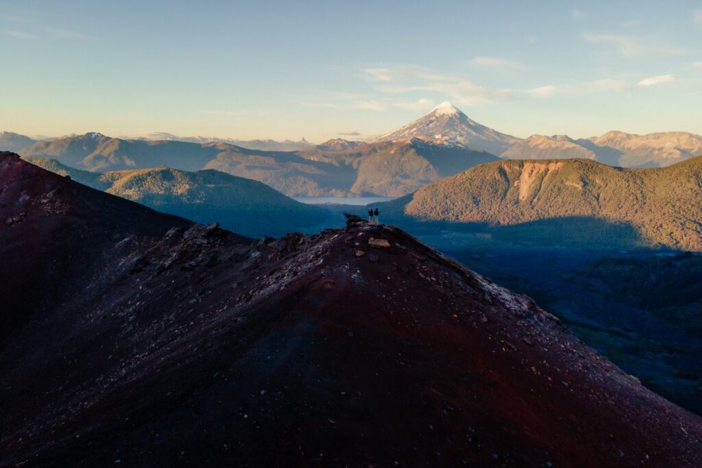 Fotografía de dos personas de pie sobre la cima de una montaá